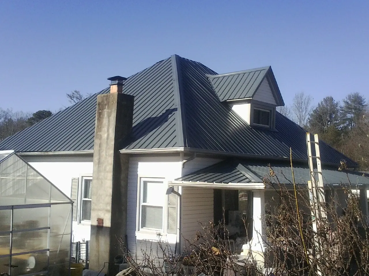 Dark blue standing seam metal roof on a white farmhouse with dormer — Slate & Tile Roof Repair by Roofing Brothers in Buzzards Bay