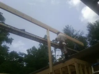 Carpenter setting a ridge beam over a new addition frame — Ice Dam Removal by Roofing Brothers in Buzzards Bay