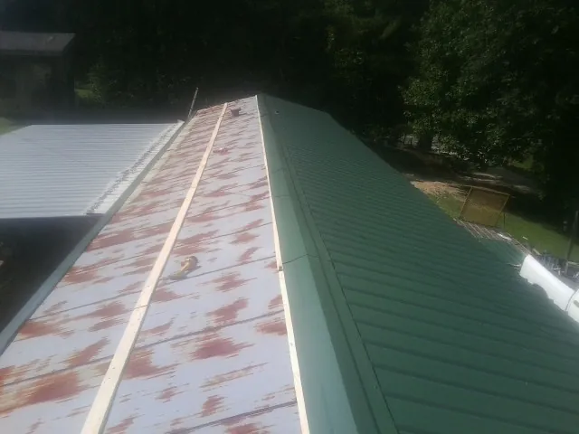 Old rusted panels beside newly installed green metal roofing — Wind Damage Roof Repair by Roofing Brothers in Buzzards Bay