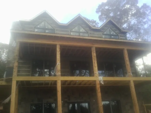 Dormers and porch framing on a large log home under construction — Roof Coating work by our crew in Buzzards Bay