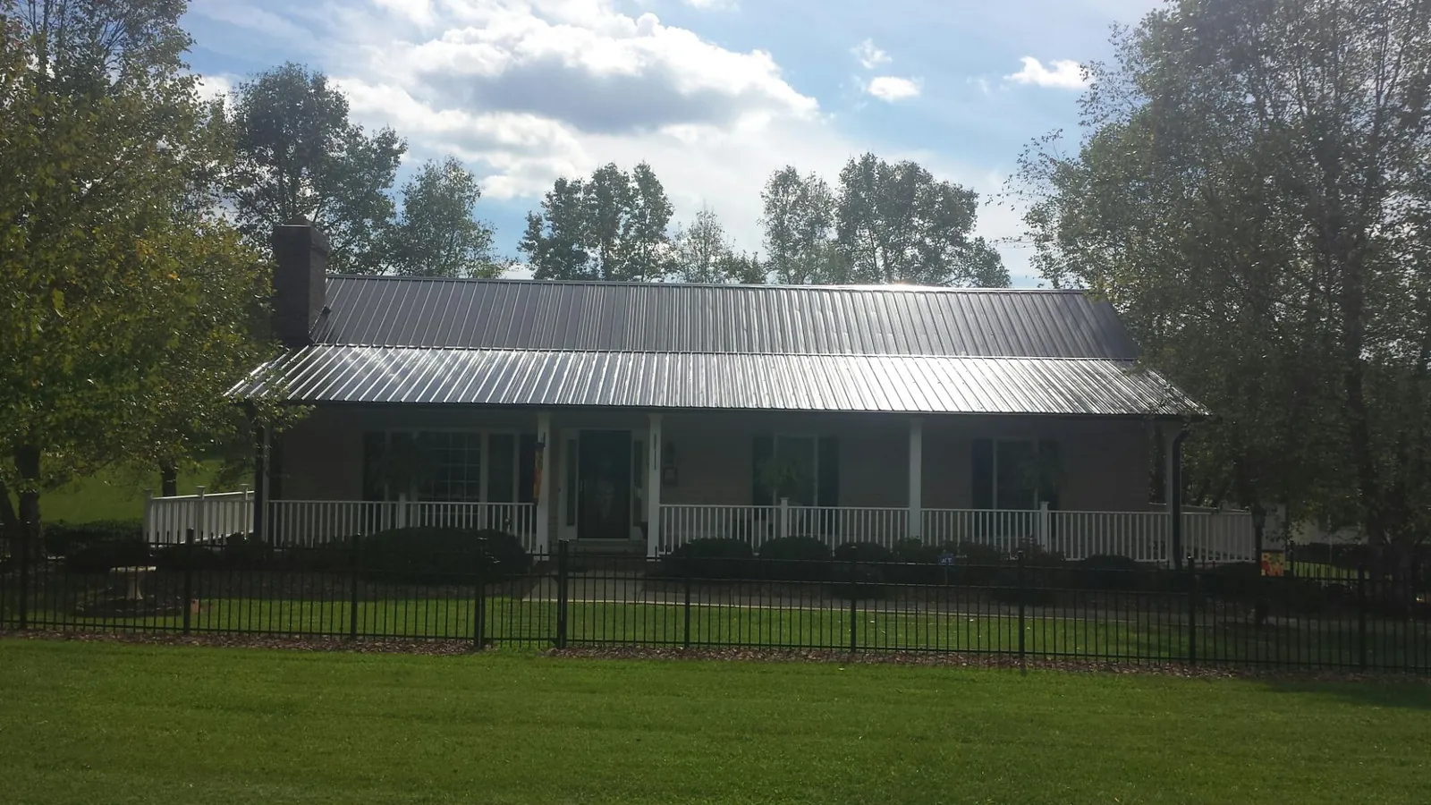 Gray metal roof on a brick ranch with a full width front porch — Gutter Guard Installation work by our crew in Buzzards Bay