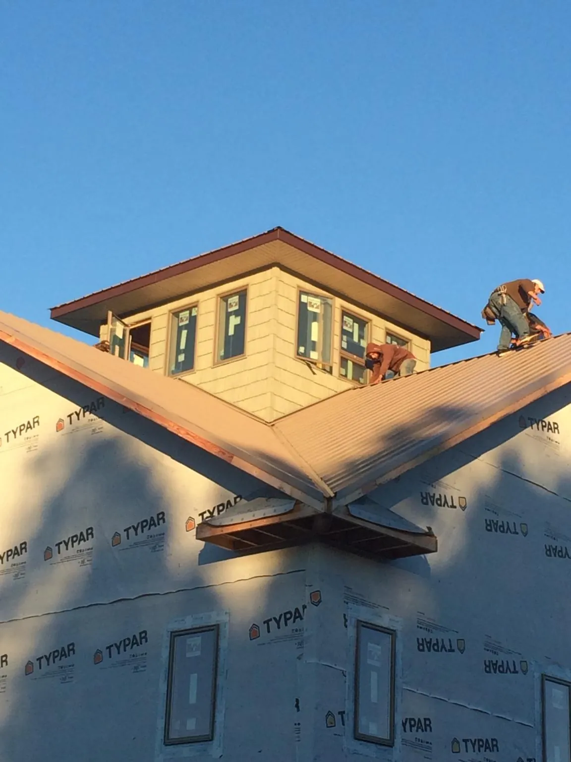 Roofers working around a rooftop cupola on a new metal roof at sunset — Roof Waterproofing in Buzzards Bay by Roofing Brothers